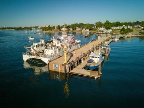 Drone shot of UNH pier, with small vessels and large NOAA ship